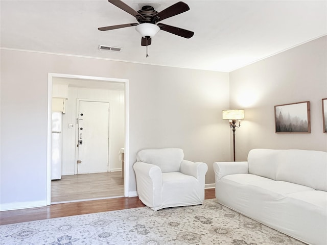 living room featuring wood-type flooring, crown molding, and ceiling fan