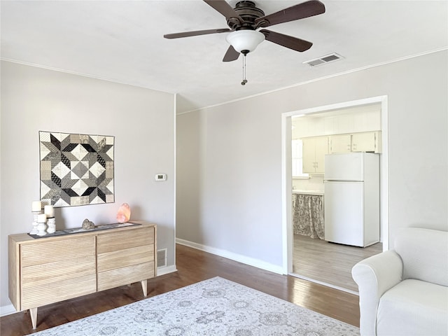 bedroom with crown molding, ensuite bath, ceiling fan, hardwood / wood-style floors, and white refrigerator