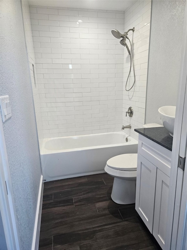 full bathroom with hardwood / wood-style floors, vanity, toilet, and tiled shower / bath