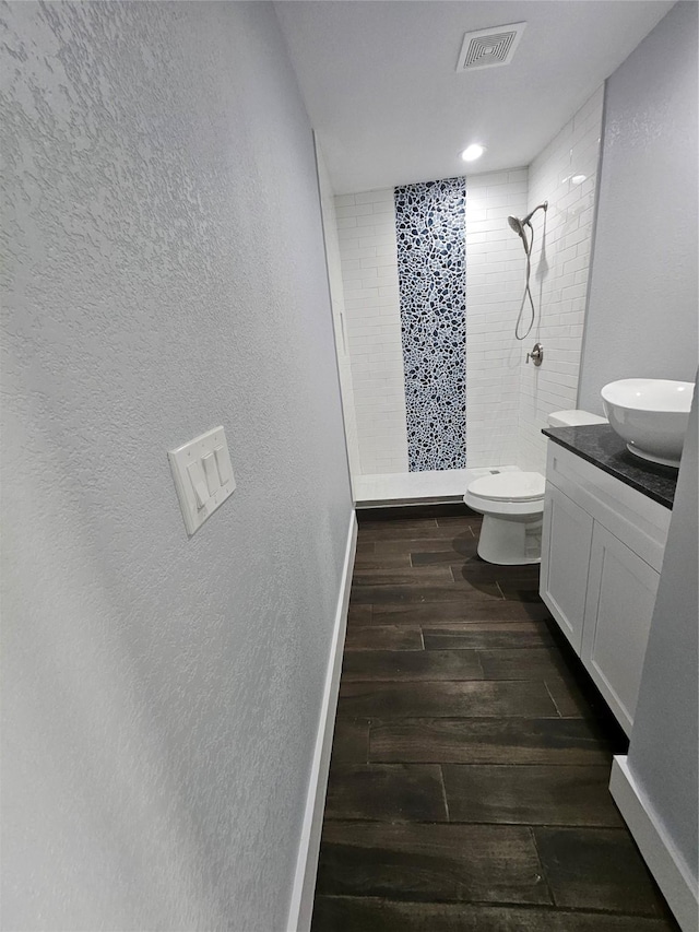 bathroom with vanity, toilet, and a tile shower