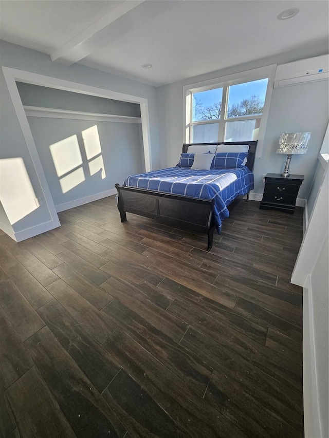 bedroom featuring beam ceiling, dark wood-type flooring, and a wall mounted AC