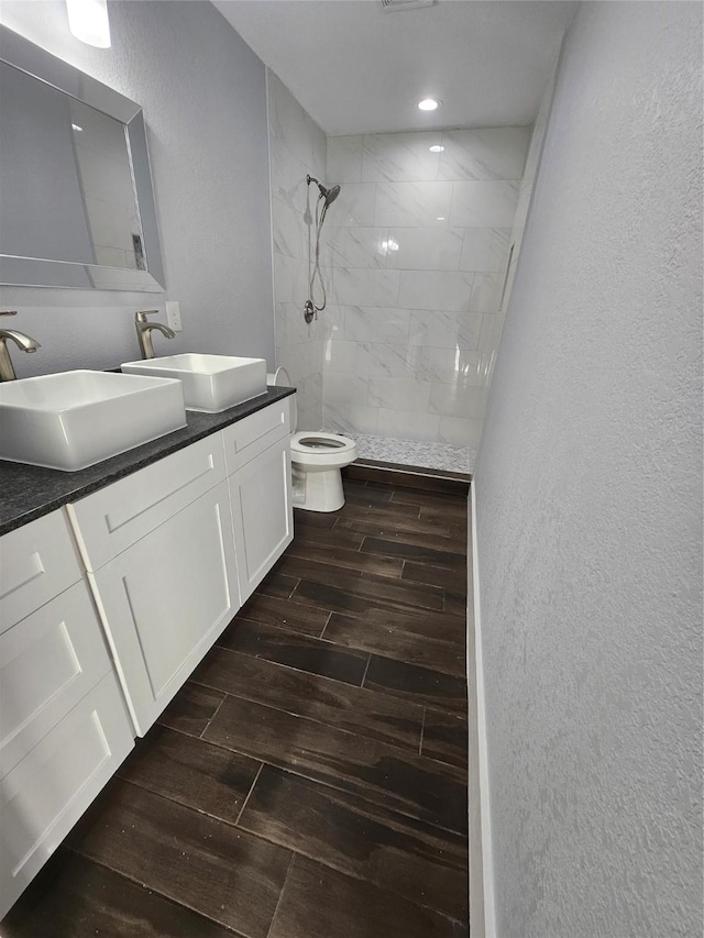 bathroom featuring a tile shower, vanity, and toilet