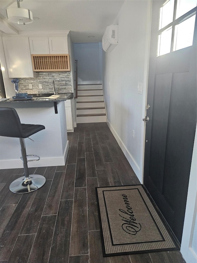 kitchen with decorative backsplash, a wall mounted air conditioner, a breakfast bar, ventilation hood, and white cabinets