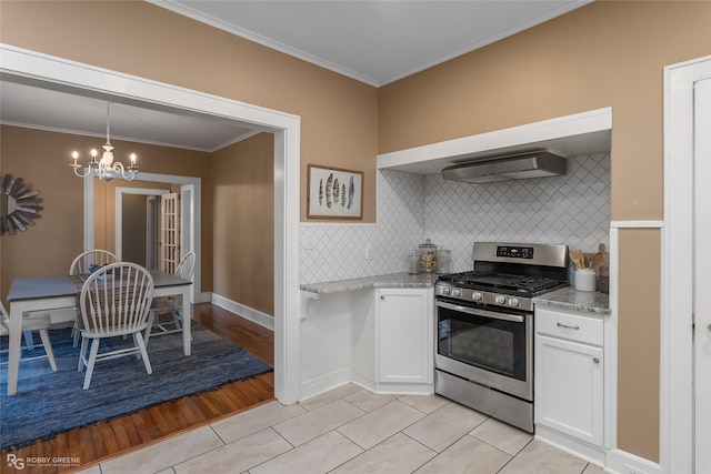 kitchen featuring tasteful backsplash, white cabinets, a chandelier, ornamental molding, and gas range