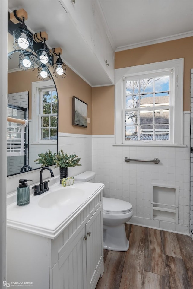 bathroom with hardwood / wood-style floors, tile walls, vanity, toilet, and crown molding