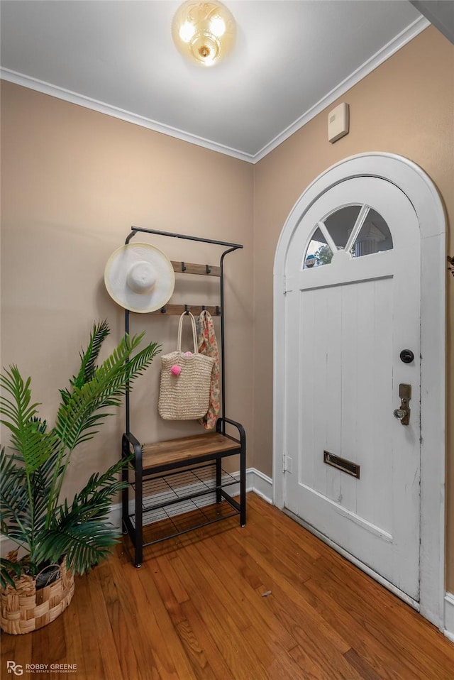 entryway with wood-type flooring and crown molding