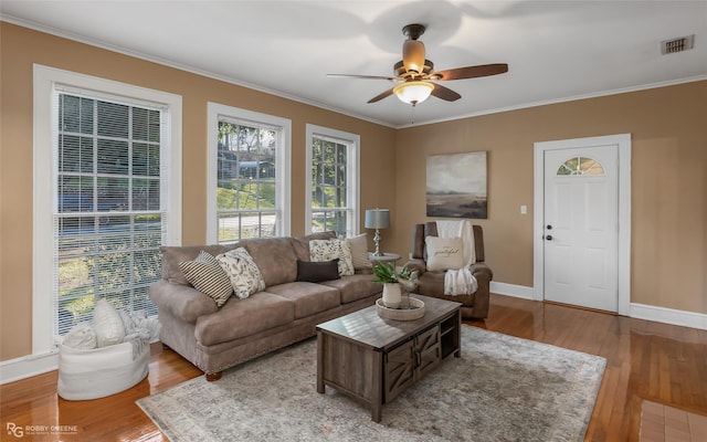 living room featuring wood-type flooring, ceiling fan, and crown molding