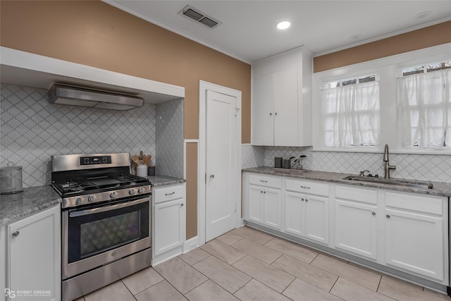 kitchen with sink, stainless steel range with gas stovetop, white cabinets, light stone countertops, and backsplash