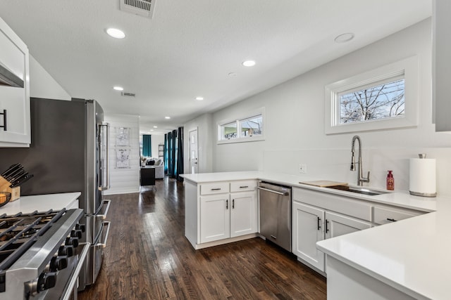 kitchen with appliances with stainless steel finishes, sink, white cabinets, and kitchen peninsula