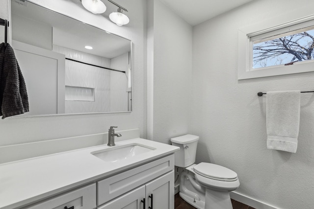 bathroom featuring vanity, toilet, and walk in shower