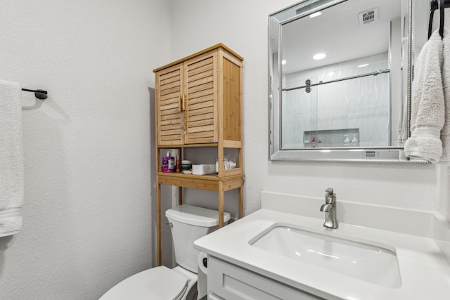 bathroom featuring vanity, toilet, and tiled shower