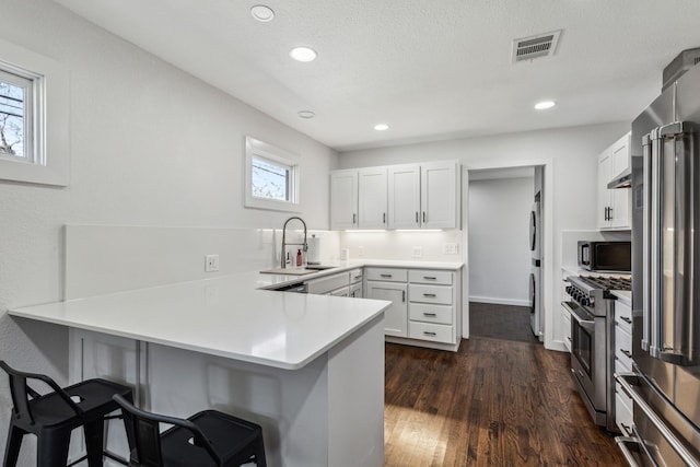 kitchen featuring a breakfast bar area, kitchen peninsula, white cabinetry, and premium appliances