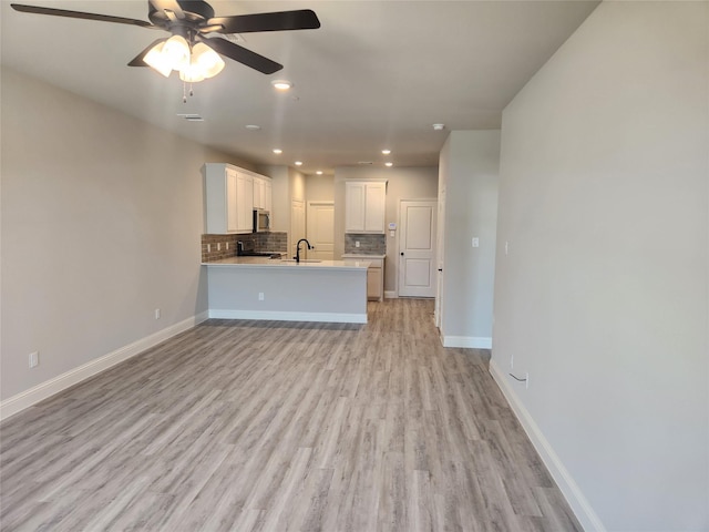 unfurnished living room featuring ceiling fan, sink, and light wood-type flooring