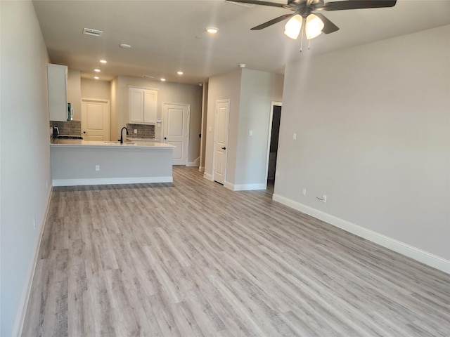 unfurnished living room with ceiling fan, light wood-type flooring, and sink