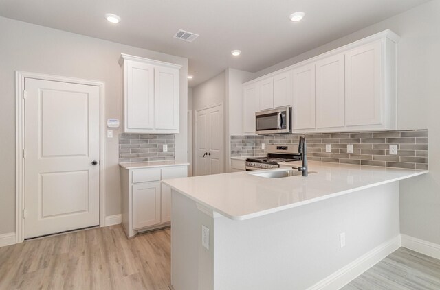 kitchen featuring kitchen peninsula, white cabinetry, sink, and appliances with stainless steel finishes