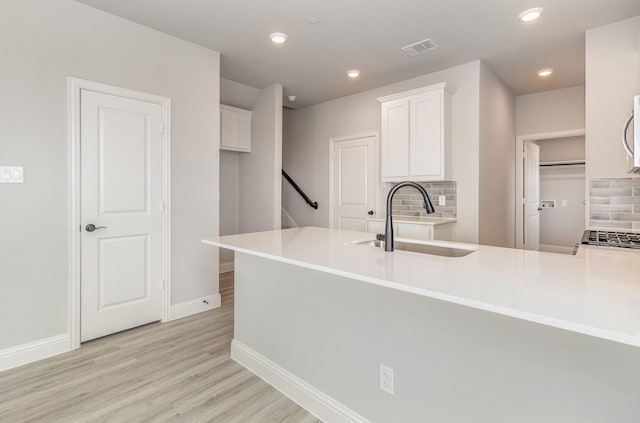 kitchen with kitchen peninsula, tasteful backsplash, white cabinetry, and sink