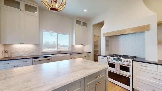 kitchen featuring stainless steel appliances, white cabinetry, hanging light fixtures, and dark stone counters