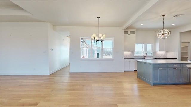 kitchen with light hardwood / wood-style flooring, white cabinets, and decorative light fixtures