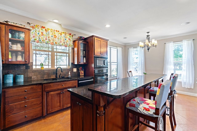 kitchen with sink, black oven, a breakfast bar area, a kitchen island, and decorative light fixtures