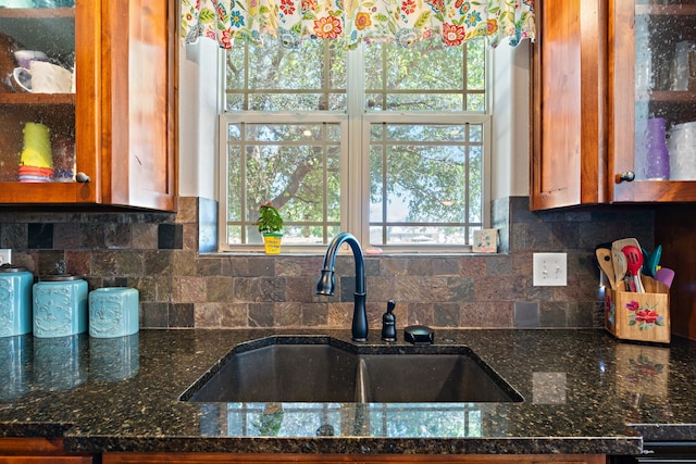 kitchen featuring tasteful backsplash, plenty of natural light, sink, and dark stone countertops