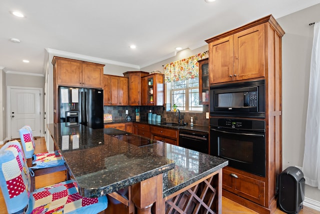 kitchen with a kitchen island, sink, a breakfast bar area, and black appliances