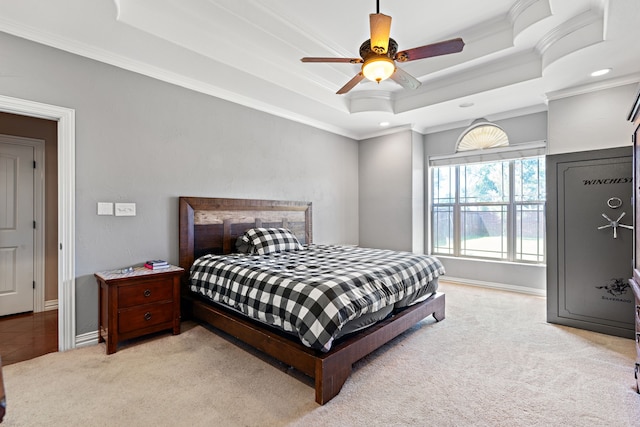 bedroom with ceiling fan, light colored carpet, ornamental molding, and a tray ceiling