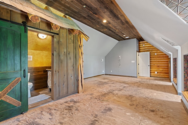 bonus room with lofted ceiling, a barn door, and rustic walls