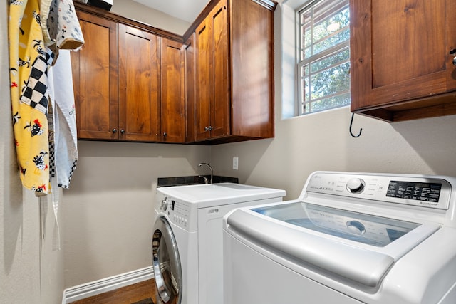 clothes washing area featuring washing machine and dryer and cabinets