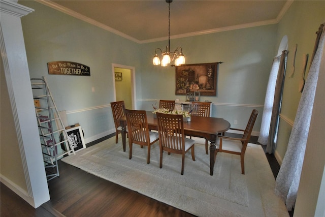 dining space with crown molding, wood-type flooring, and an inviting chandelier