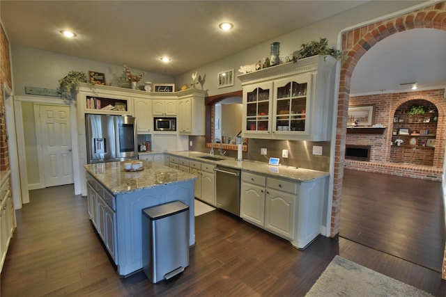 kitchen with a center island, brick wall, dark hardwood / wood-style flooring, and appliances with stainless steel finishes