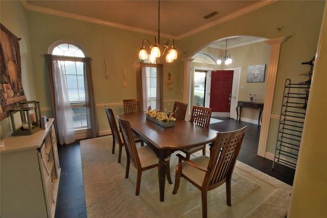 dining space with wood-type flooring, ornamental molding, and an inviting chandelier