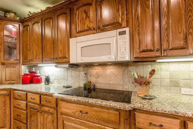 kitchen featuring black electric cooktop, light stone countertops, and backsplash