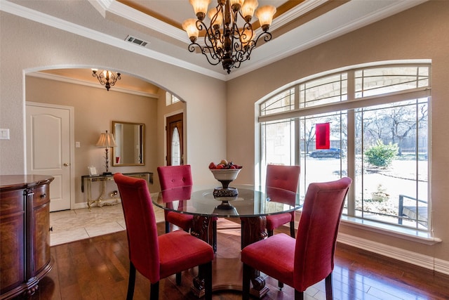 dining area featuring dark hardwood / wood-style floors, ornamental molding, a tray ceiling, and a chandelier