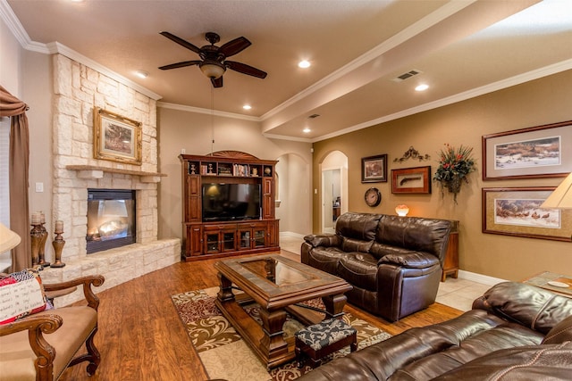 living room with crown molding, ceiling fan, a fireplace, and light hardwood / wood-style flooring