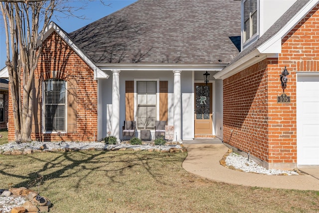 doorway to property featuring a garage, a yard, and covered porch