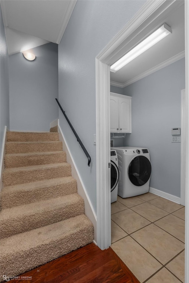 laundry room with cabinets, ornamental molding, washing machine and dryer, and light tile patterned floors