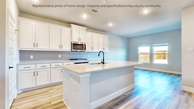 kitchen featuring sink, white cabinets, a center island with sink, and light hardwood / wood-style flooring