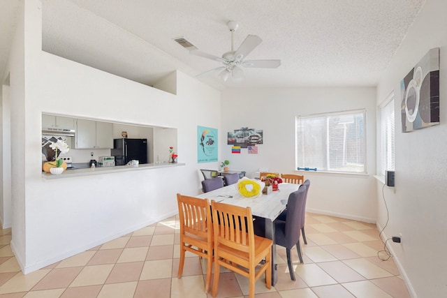 tiled dining room with vaulted ceiling, ceiling fan, and a textured ceiling