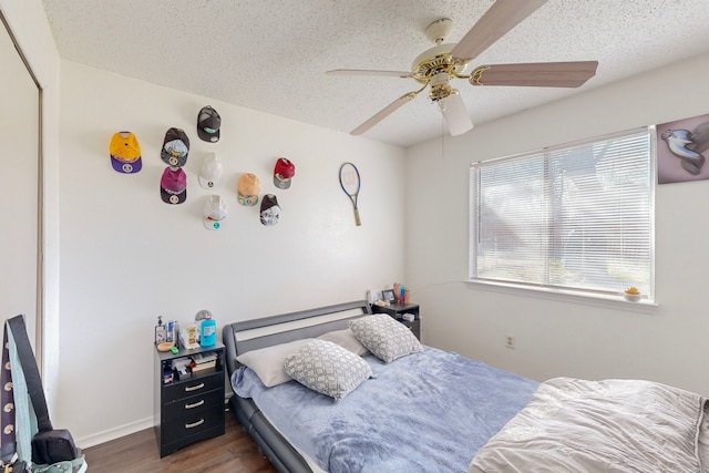 bedroom featuring ceiling fan, a textured ceiling, and dark wood-type flooring