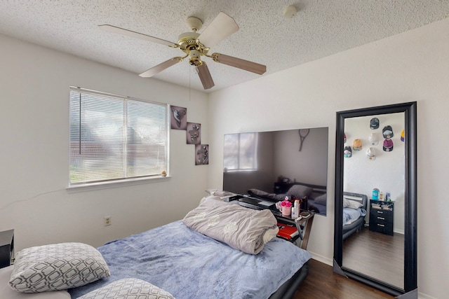 bedroom with ceiling fan, dark hardwood / wood-style flooring, and a textured ceiling