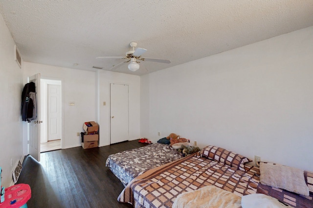 bedroom with dark hardwood / wood-style flooring, a textured ceiling, and ceiling fan