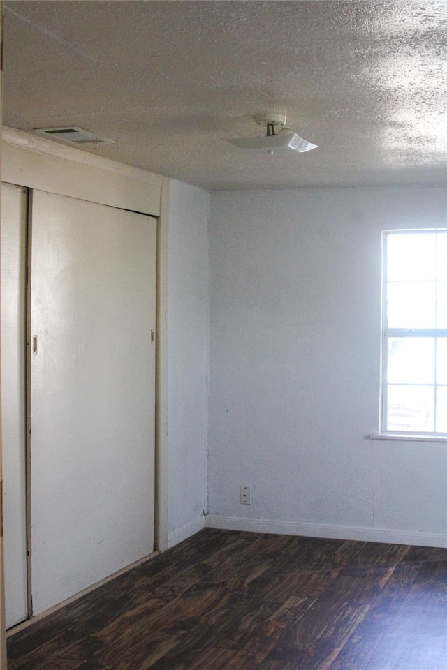 unfurnished room with dark hardwood / wood-style flooring and a textured ceiling