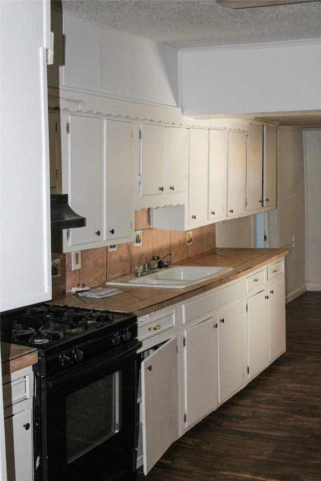 kitchen with black range with gas stovetop, tile counters, sink, and white cabinets