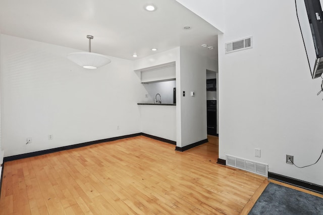 unfurnished living room featuring wood-type flooring and sink