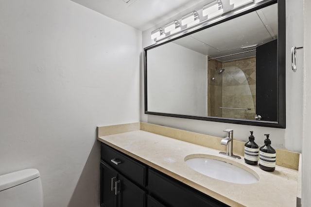 bathroom featuring tiled shower, vanity, and toilet