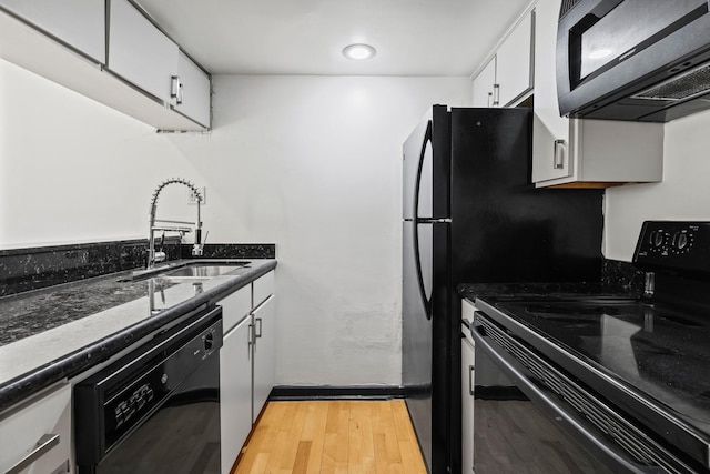 kitchen featuring dark stone counters, sink, black appliances, light hardwood / wood-style floors, and white cabinetry