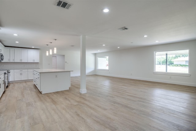 kitchen featuring light wood-type flooring, backsplash, pendant lighting, a center island, and white cabinetry