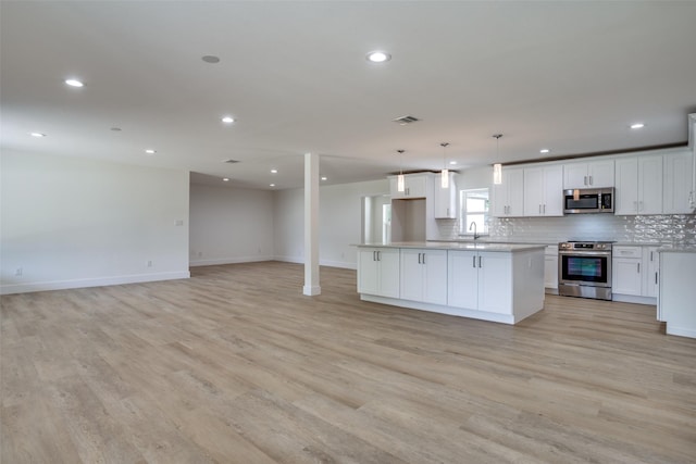 kitchen with white cabinets, appliances with stainless steel finishes, light wood-type flooring, and pendant lighting