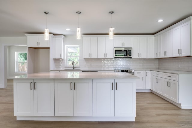 kitchen featuring white cabinetry, a center island, stainless steel appliances, and decorative light fixtures