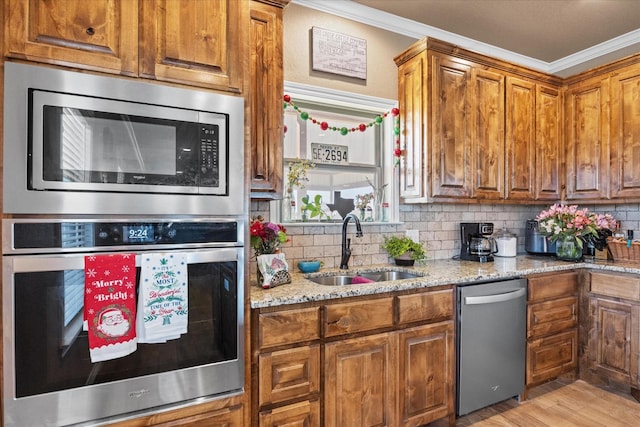 kitchen with sink, stainless steel appliances, light stone counters, crown molding, and decorative backsplash